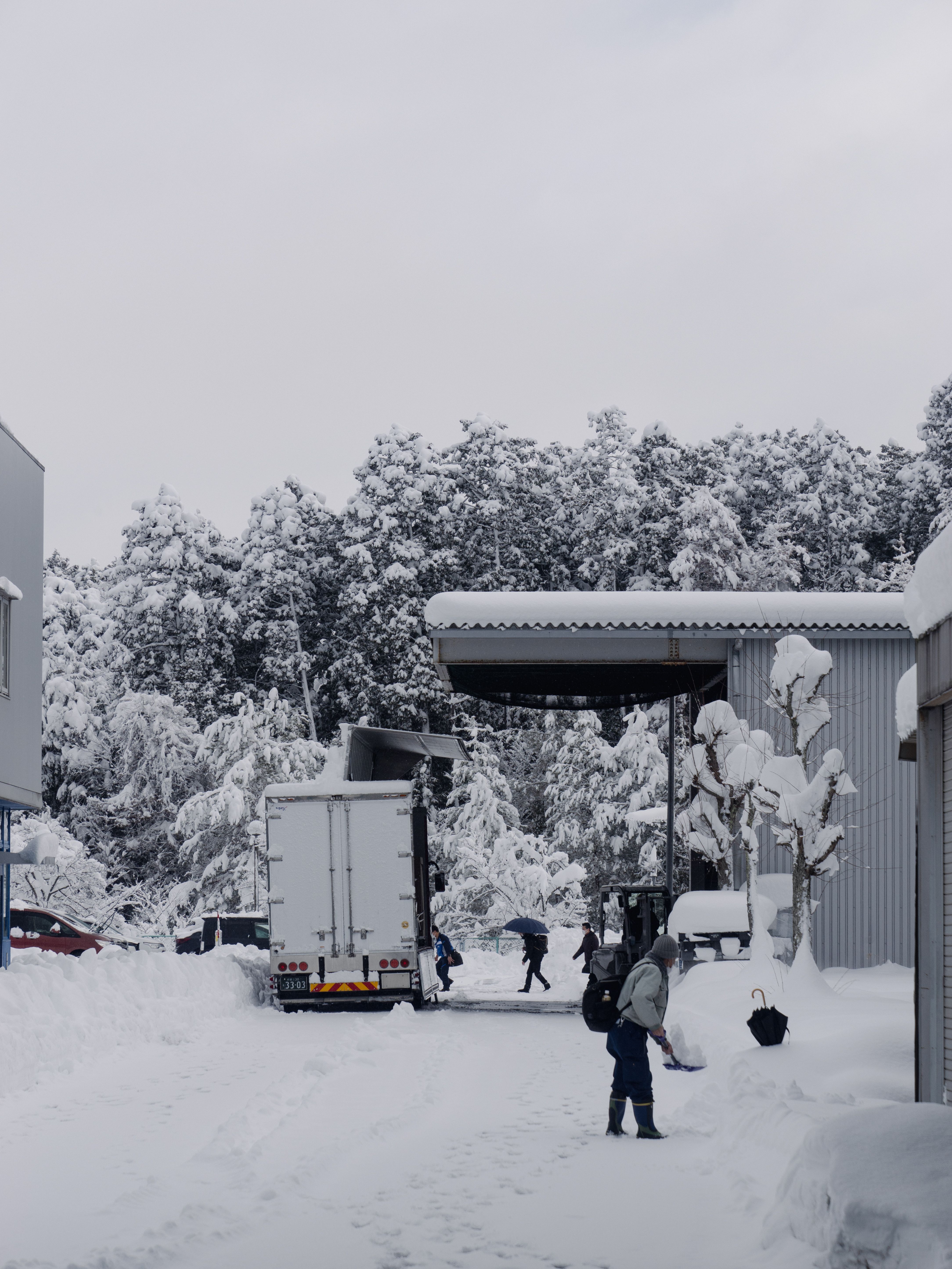 Bulk delivery truck unloading at a snow-covered commercial facility